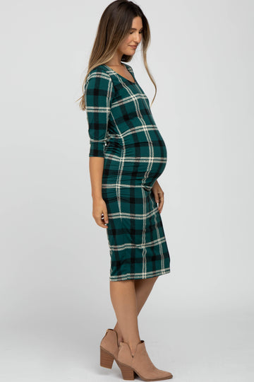 woman wearing a green and navy plaid maternity dress with a visible baby bump and three-quarter sleeves