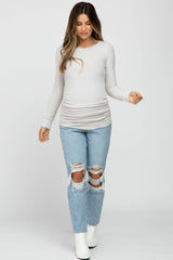 woman wearing a light grey maternity long sleeve top with ruched sides and distressed jeans, showcasing a baby bump