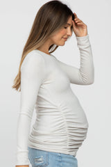 woman wearing a white long sleeve maternity top with side ruching and a visible baby bump