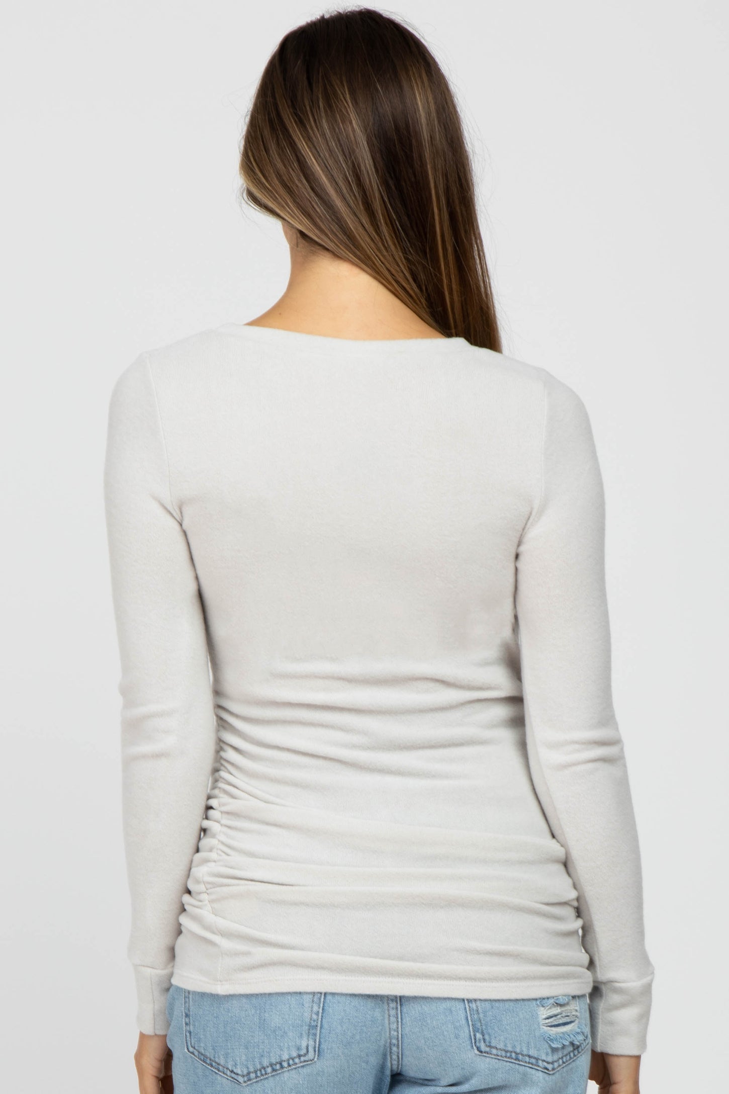 woman wearing a light grey long sleeve maternity top with ruching at the sides, view from the back