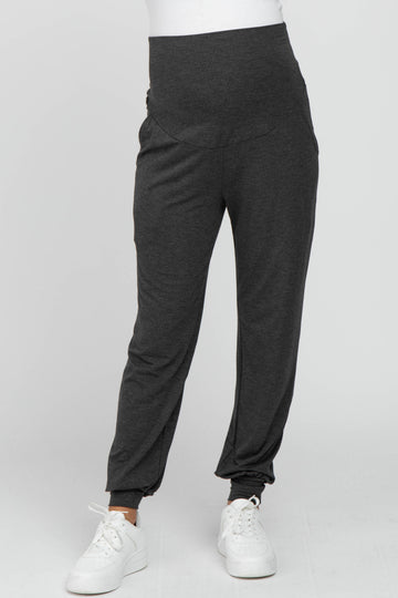 woman wearing dark grey maternity joggers with a high waistband and side pockets