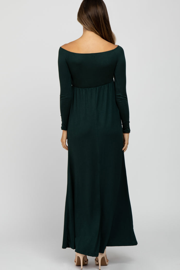 woman wearing a dark green off-shoulder maternity maxi dress with long sleeves, showing a flowing silhouette from the back