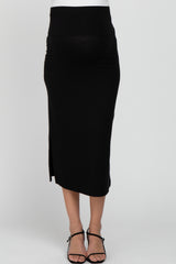 woman wearing a black maternity skirt with a side slit and a fitted waistband, showcasing her baby bump