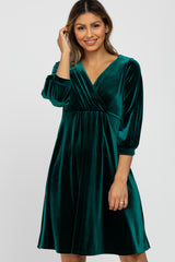 woman wearing a green velvet wrap dress with three-quarter sleeves and a flared skirt