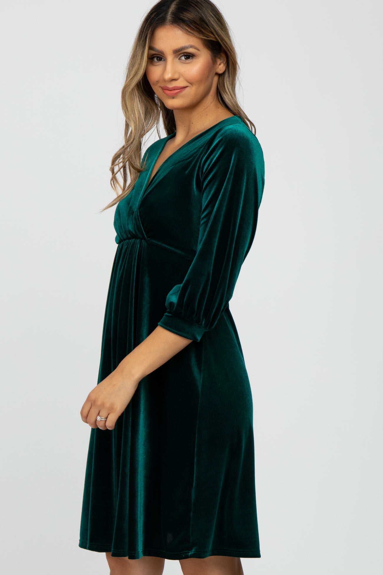 woman wearing a green velvet wrap dress with three-quarter sleeves and a fitted waistline