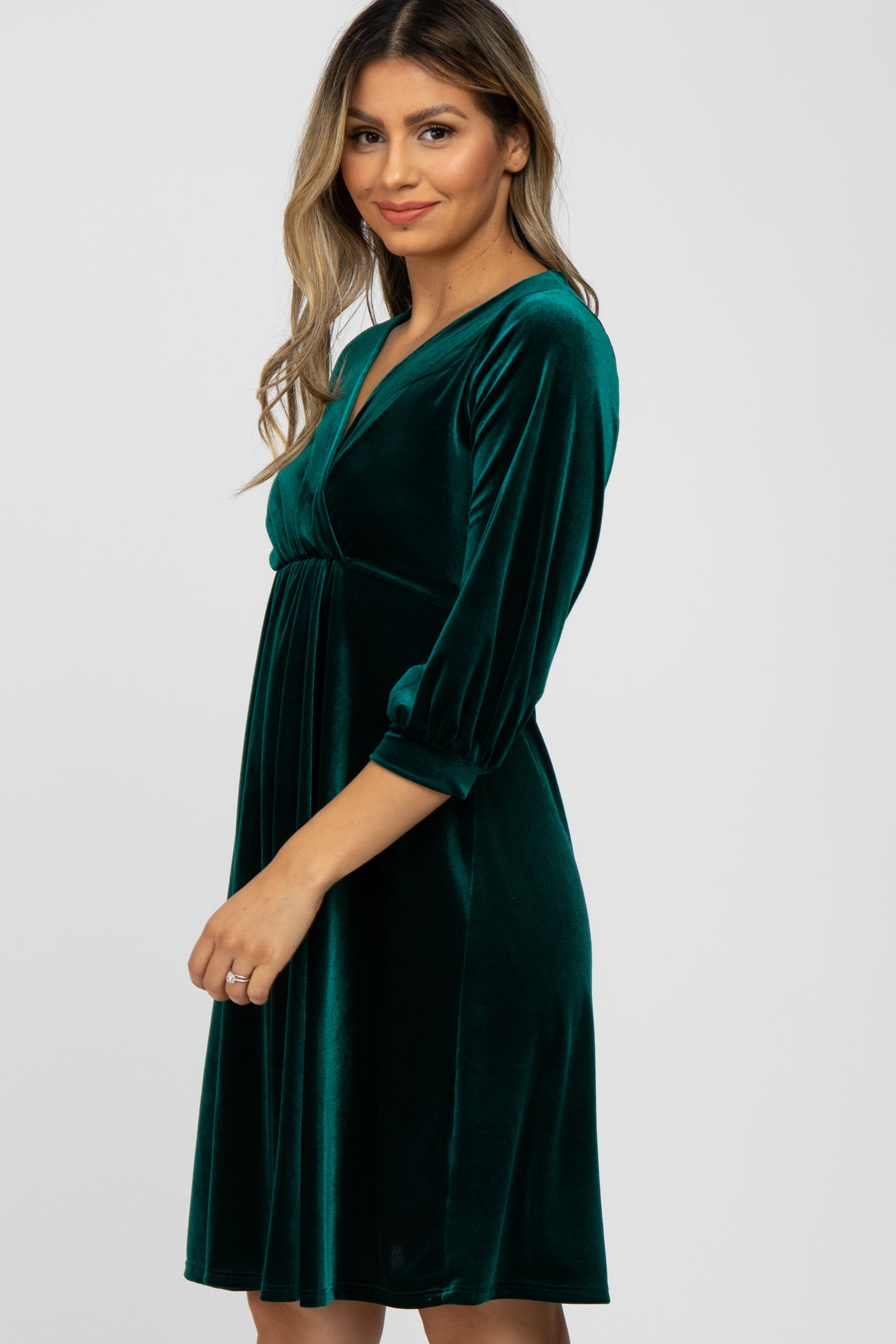 woman wearing a green velvet wrap dress with three-quarter sleeves and a fitted waistline