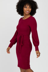 woman wearing a maroon long sleeve dress with a belted waist and balloon sleeves