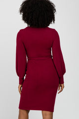 woman wearing a burgundy long sleeve dress with a fitted silhouette and puffed sleeves, shown from the back