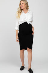 woman wearing a white button-up shirt knotted at the waist and a black maternity pencil skirt, showing her baby bump