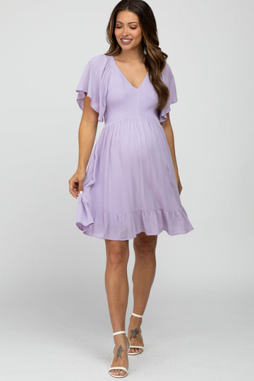 woman wearing a lilac maternity dress with flutter sleeves and a ruffled hem, showing off her baby bump