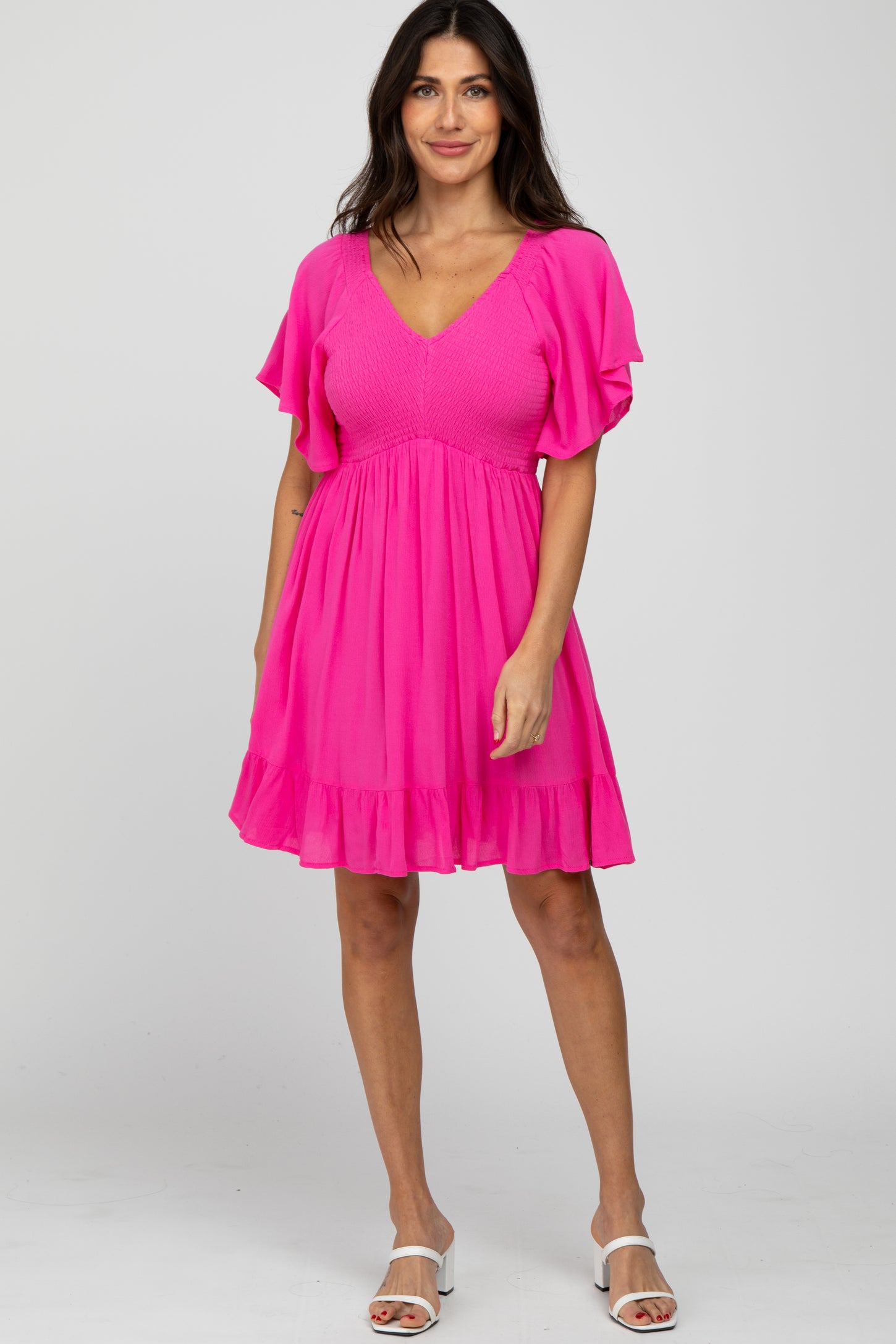 woman wearing a bright pink short sleeve dress with a smocked bodice and ruffled hem