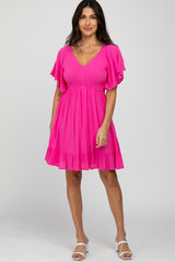 woman wearing a bright pink short sleeve dress with a smocked bodice and ruffled hem