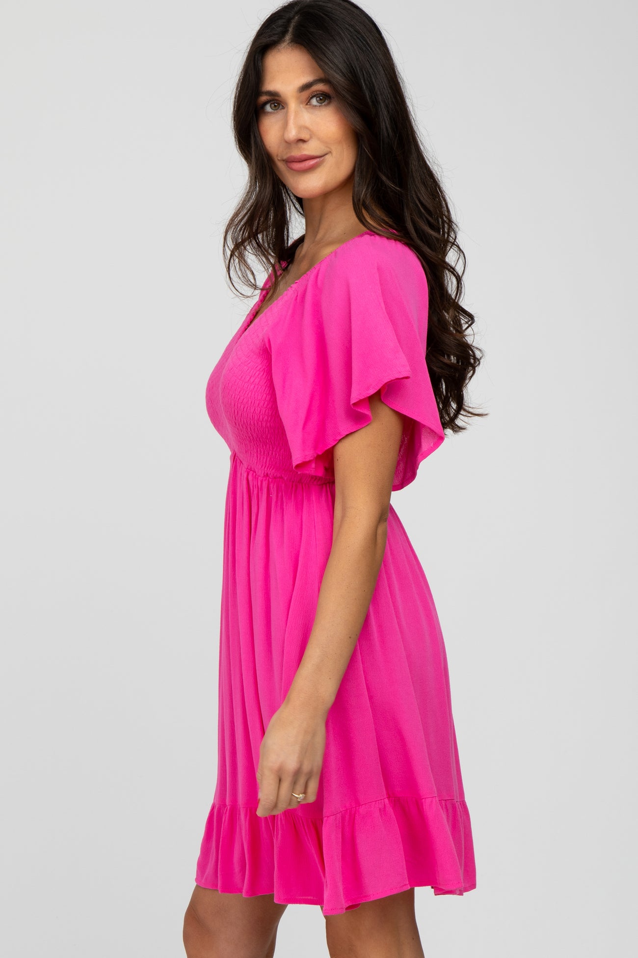woman wearing a bright pink short dress with flutter sleeves and a smocked bodice