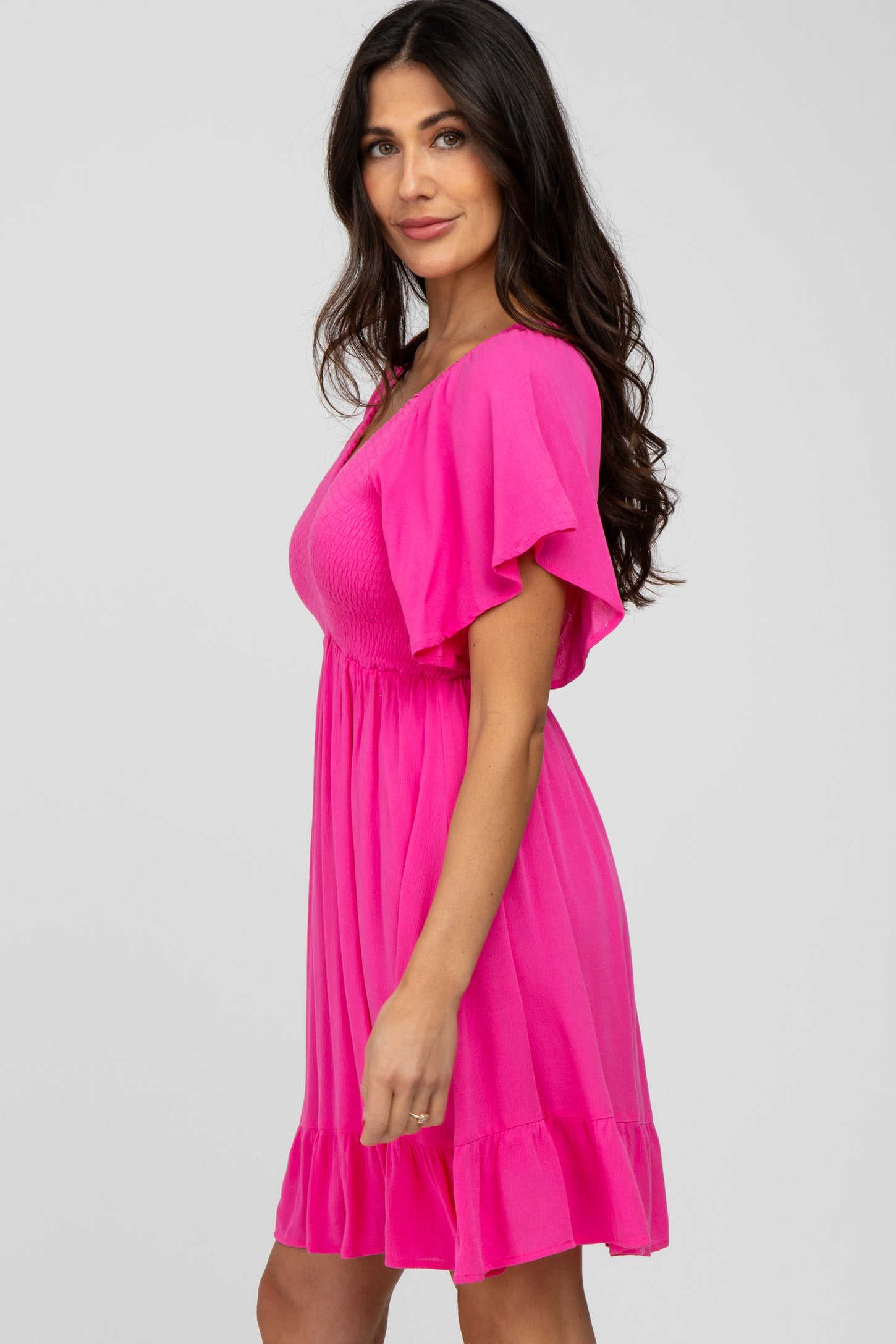 woman wearing a bright pink short dress with flutter sleeves and a smocked bodice