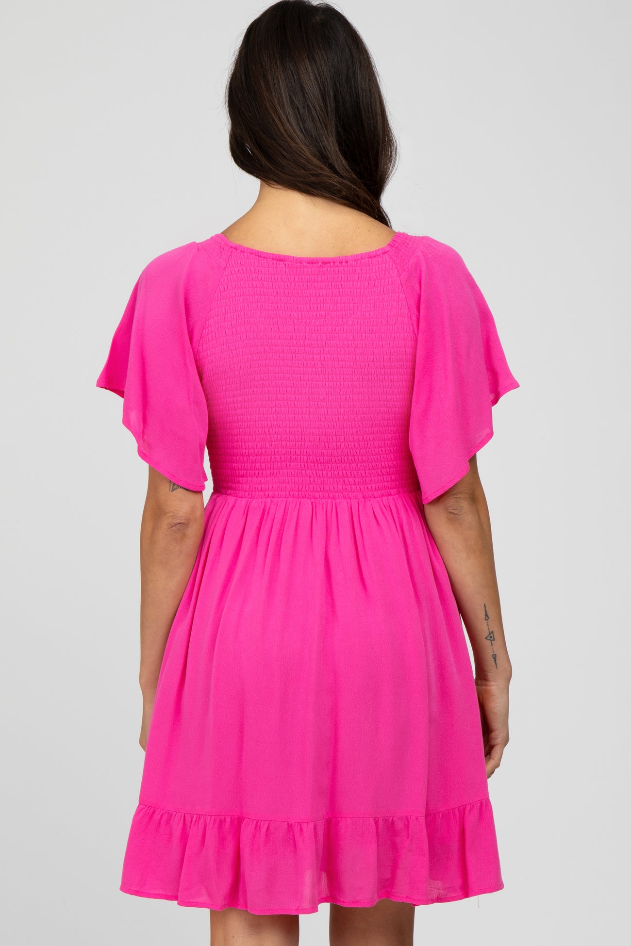 woman wearing a hot pink shimmery short dress with flutter sleeves and a ruffled hemline