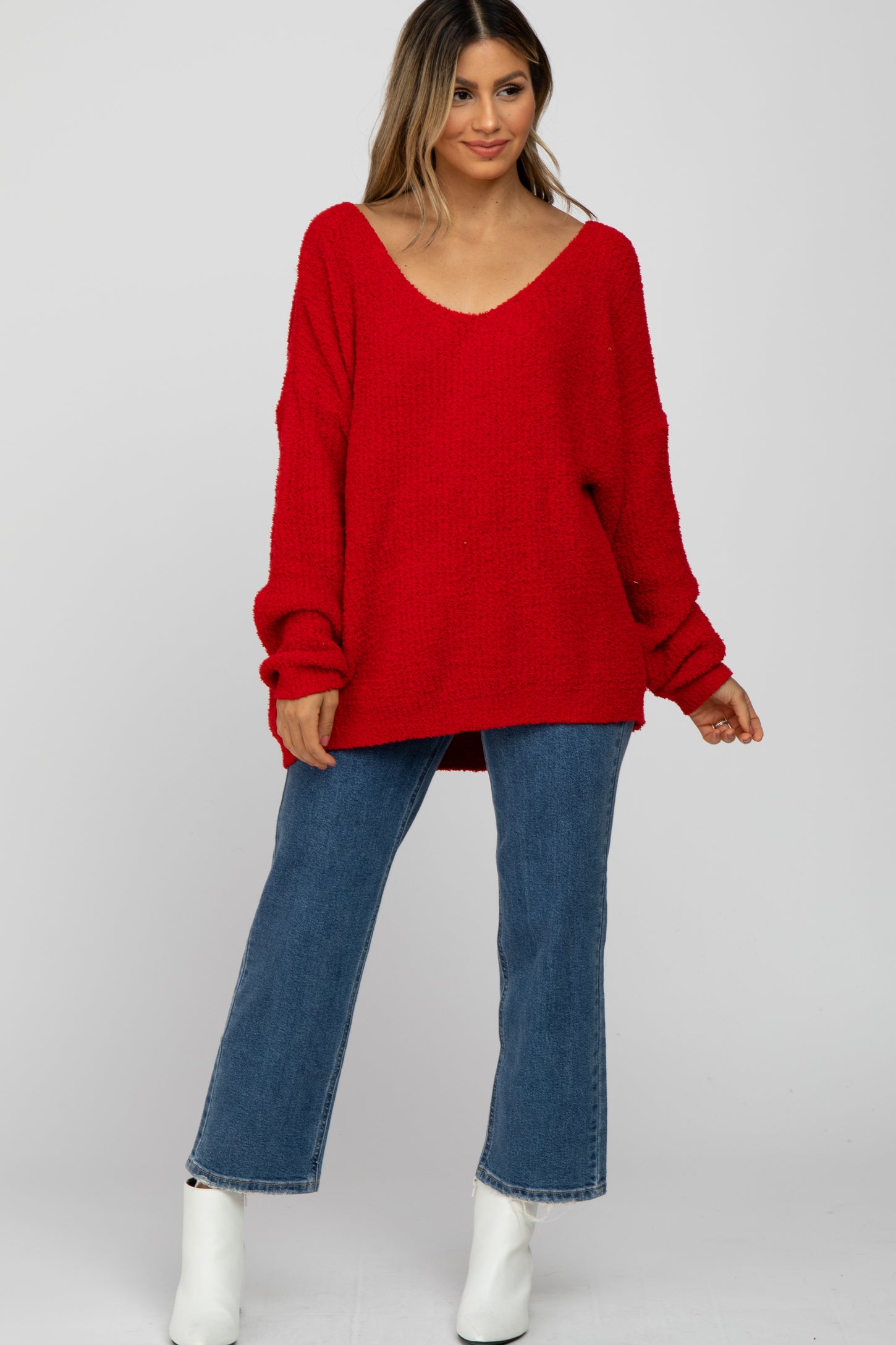 woman wearing a red oversized knit sweater with a v-neck and blue wide-leg jeans