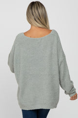 back view of a woman wearing an oversized light green fuzzy knit sweater and blue jeans