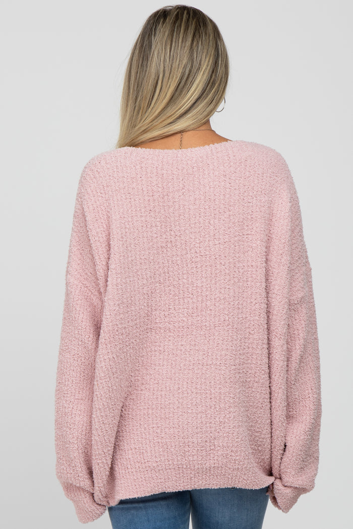 woman wearing a soft pink oversized maternity sweater, shown from the back with a relaxed fit and wide sleeves