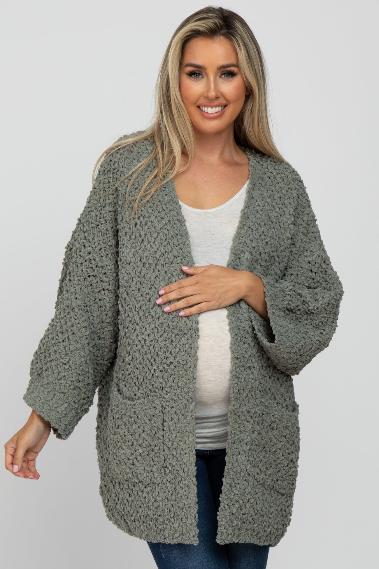 woman wearing a cozy olive green maternity cardigan and holding her baby bump