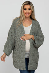 woman wearing a cozy olive green maternity cardigan and holding her baby bump