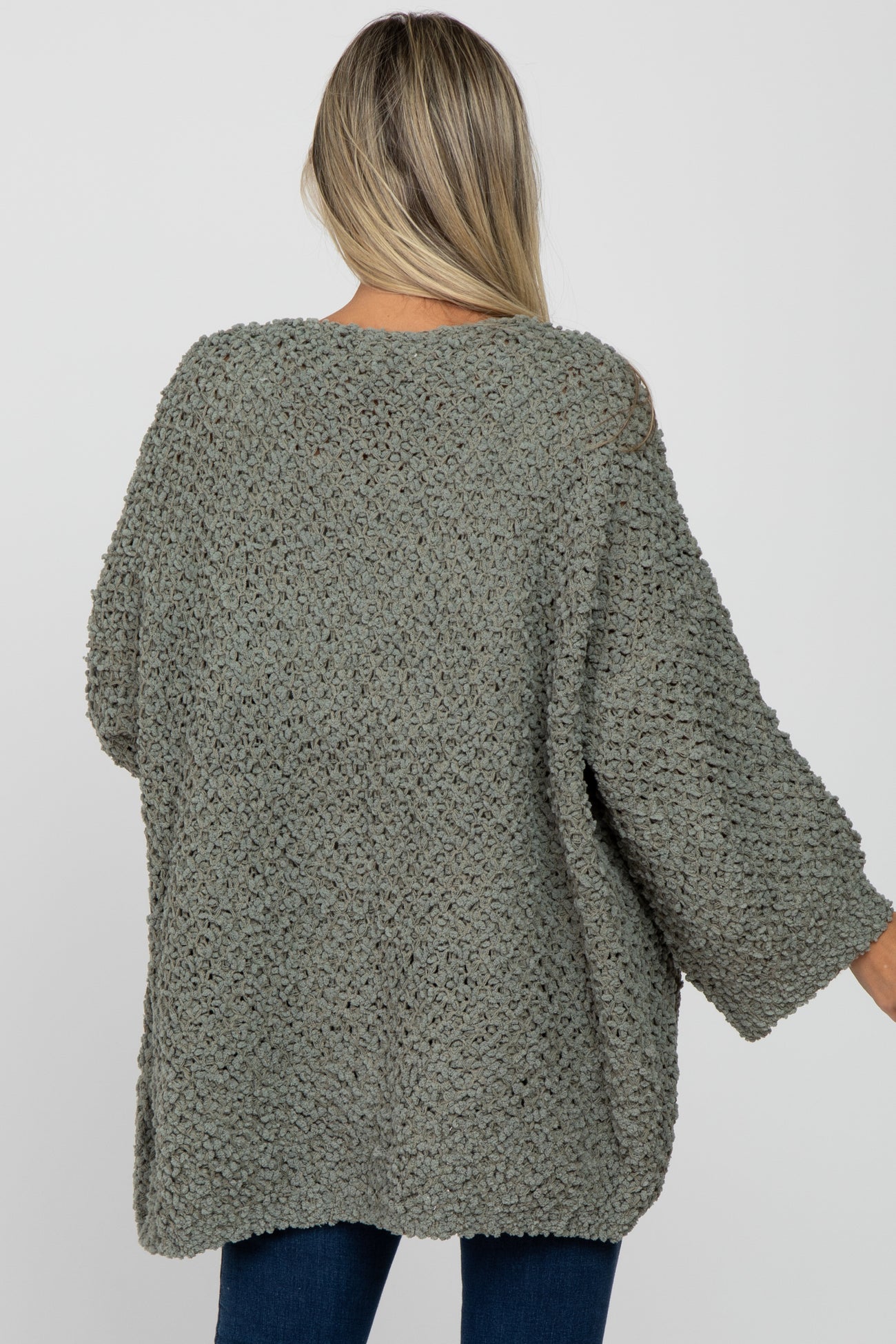 woman wearing a light green oversized maternity sweater with a cozy textured knit and three-quarter sleeves