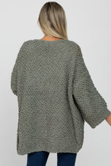 woman wearing a light green oversized maternity sweater with a cozy textured knit and three-quarter sleeves