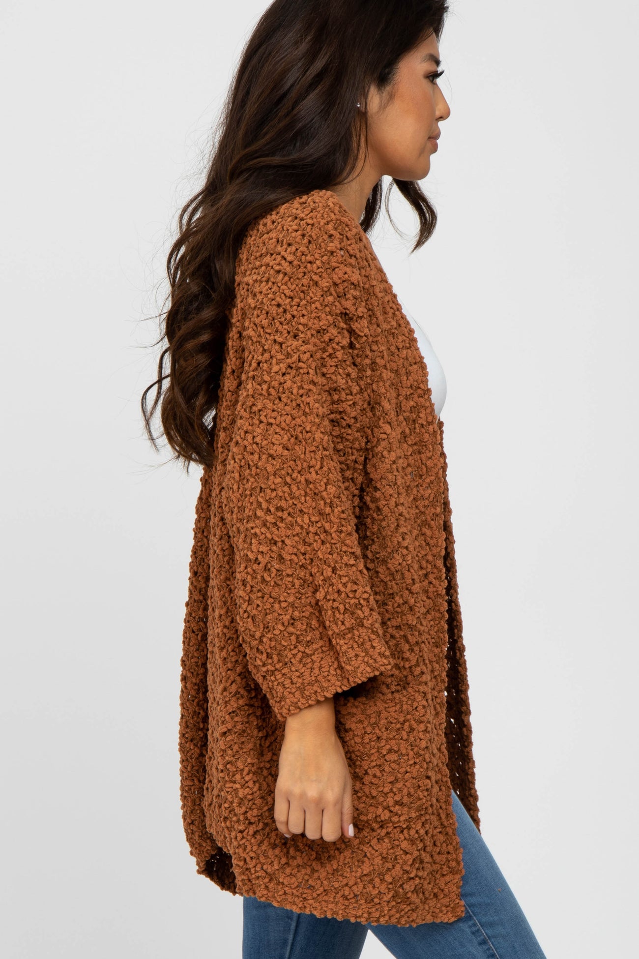 woman wearing a rust oversized chunky knit cardigan with three-quarter sleeves and a relaxed fit
