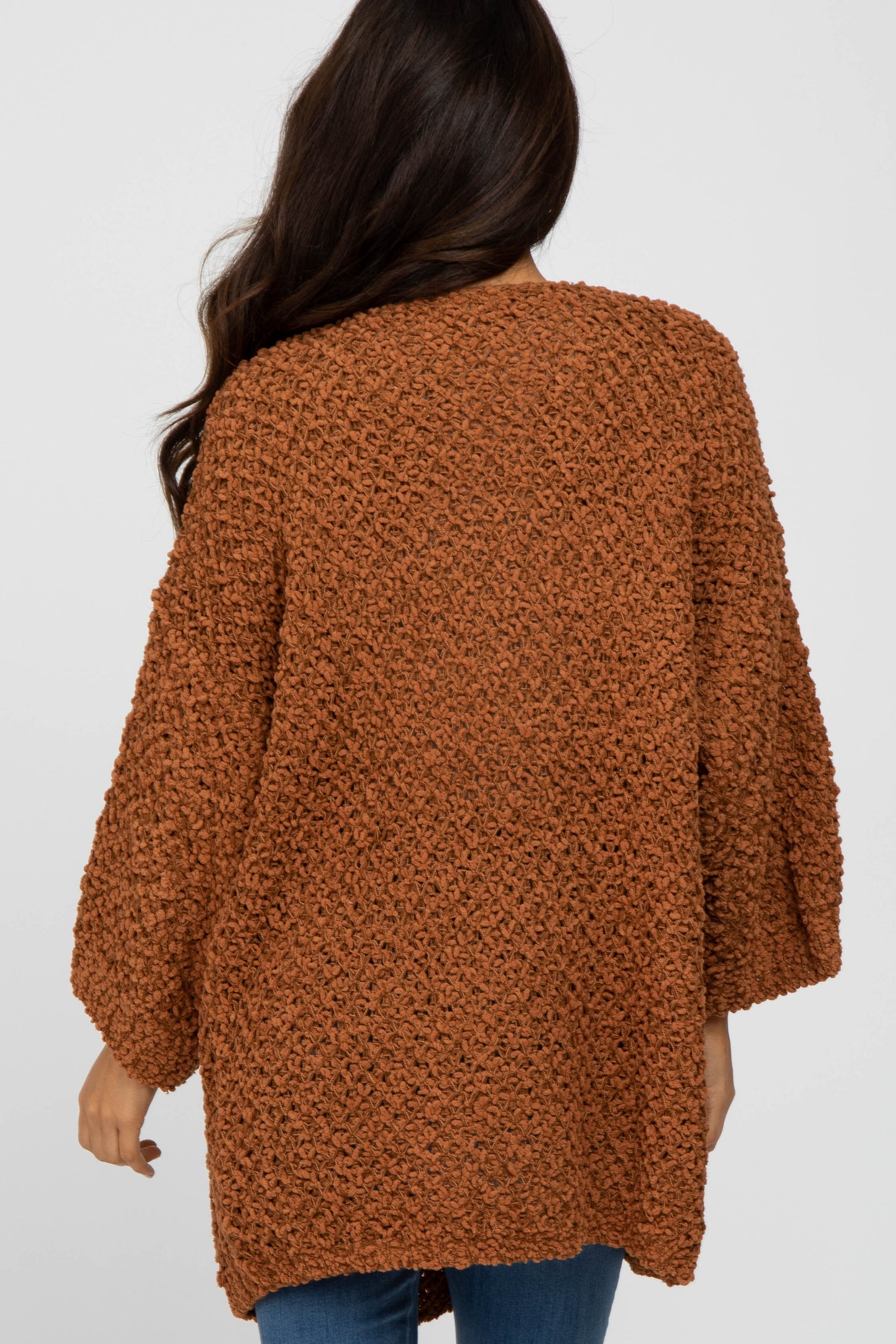woman wearing a cozy oversized brown knit sweater with three-quarter sleeves and an open back design