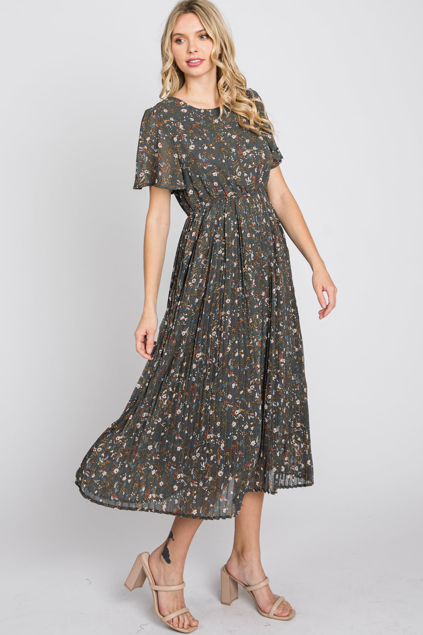 woman wearing a dark green floral maxi dress with short flutter sleeves and a pleated skirt