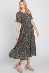 woman wearing a dark green floral maxi dress with short flutter sleeves and a pleated skirt