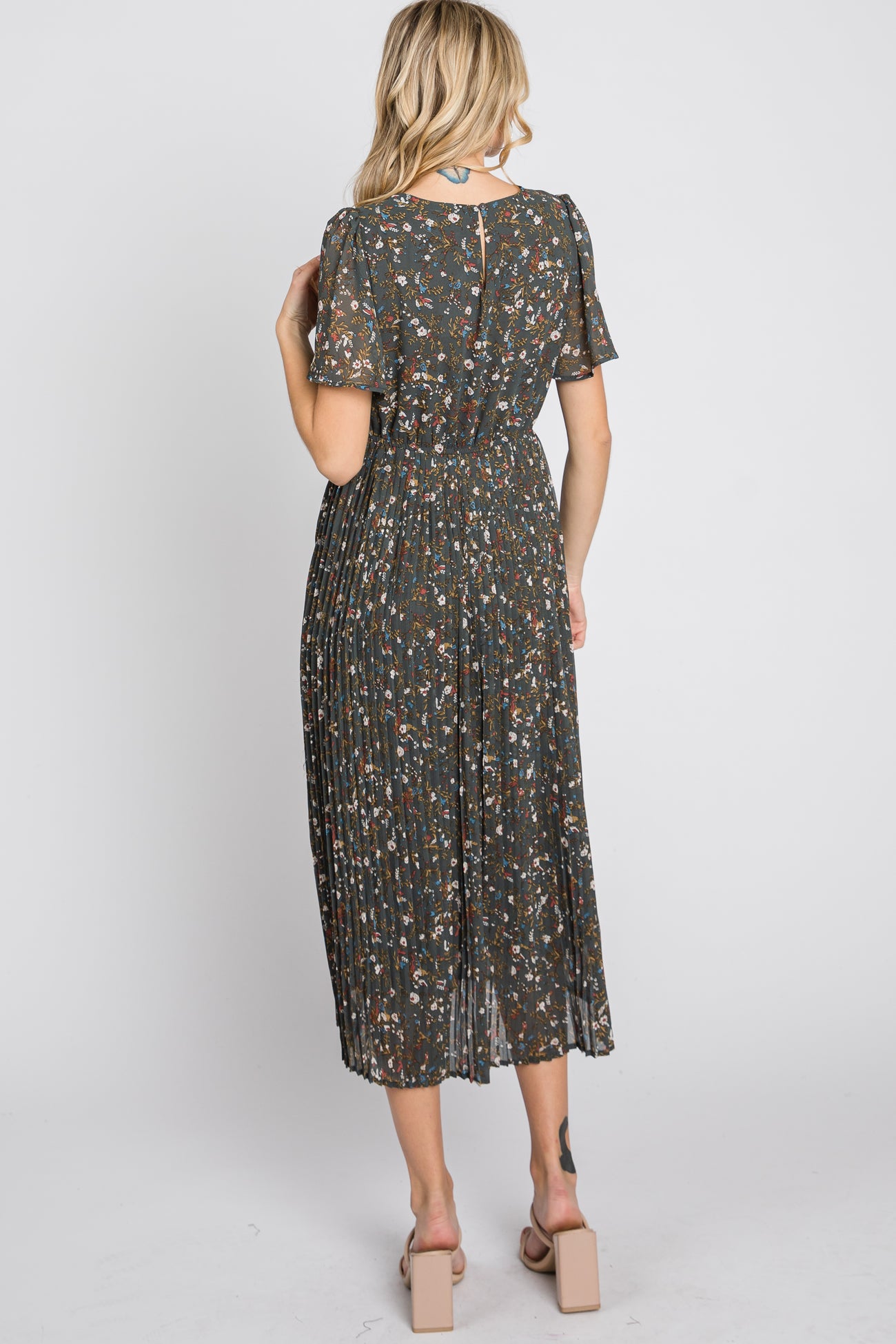 woman wearing a floral pleated midi dress with short sleeves, seen from the back