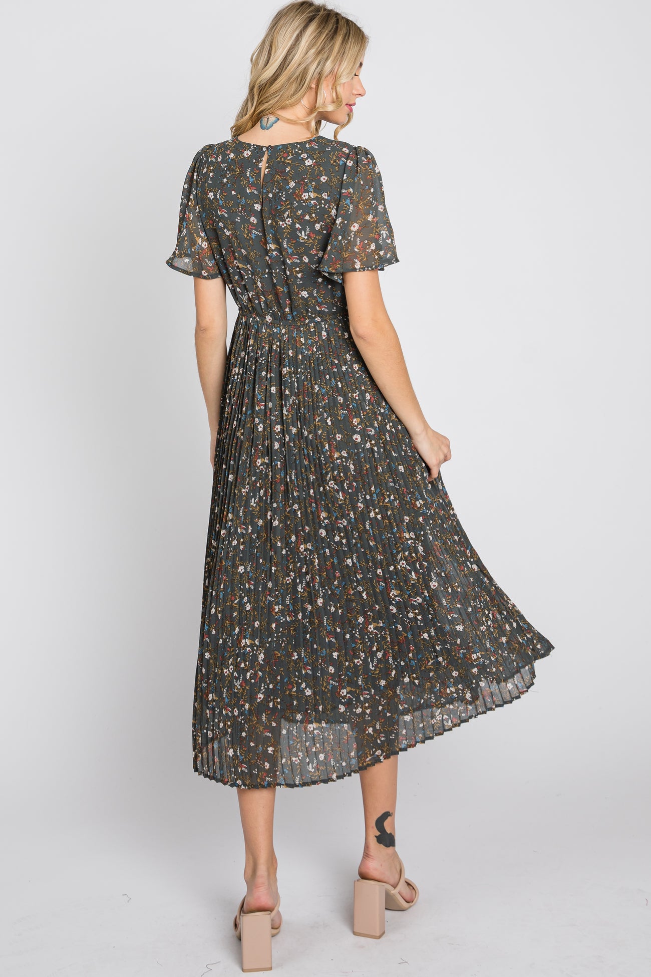woman wearing a dark floral midi dress with pleated skirt and short sleeves, shown from the back