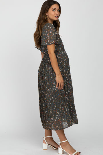 woman wearing a dark floral print maternity dress with pleated details and a visible baby bump