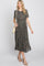 woman wearing a black floral pleated maxi dress with short sleeves and holding a cream crossbody bag
