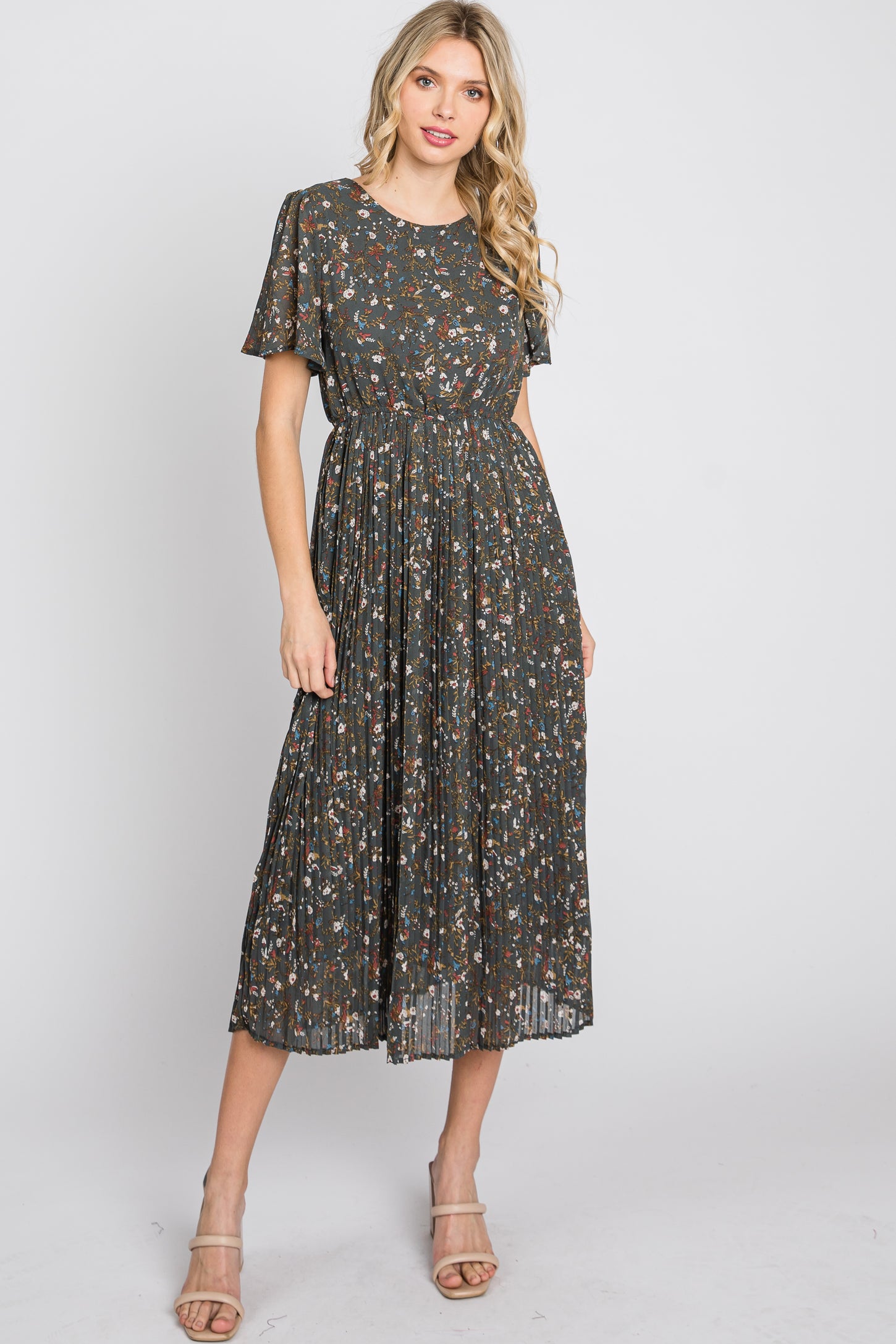 woman wearing a dark floral midi dress with short sleeves and pleated skirt, standing in a casual pose
