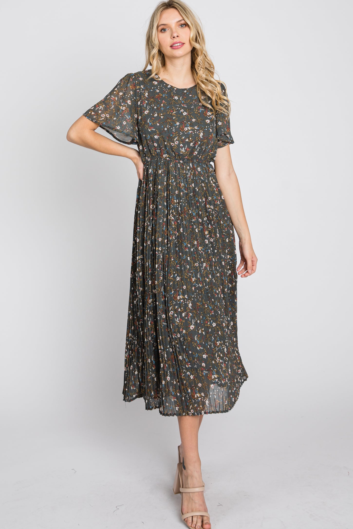 woman wearing a dark green floral maxi dress with short sleeves and a pleated skirt