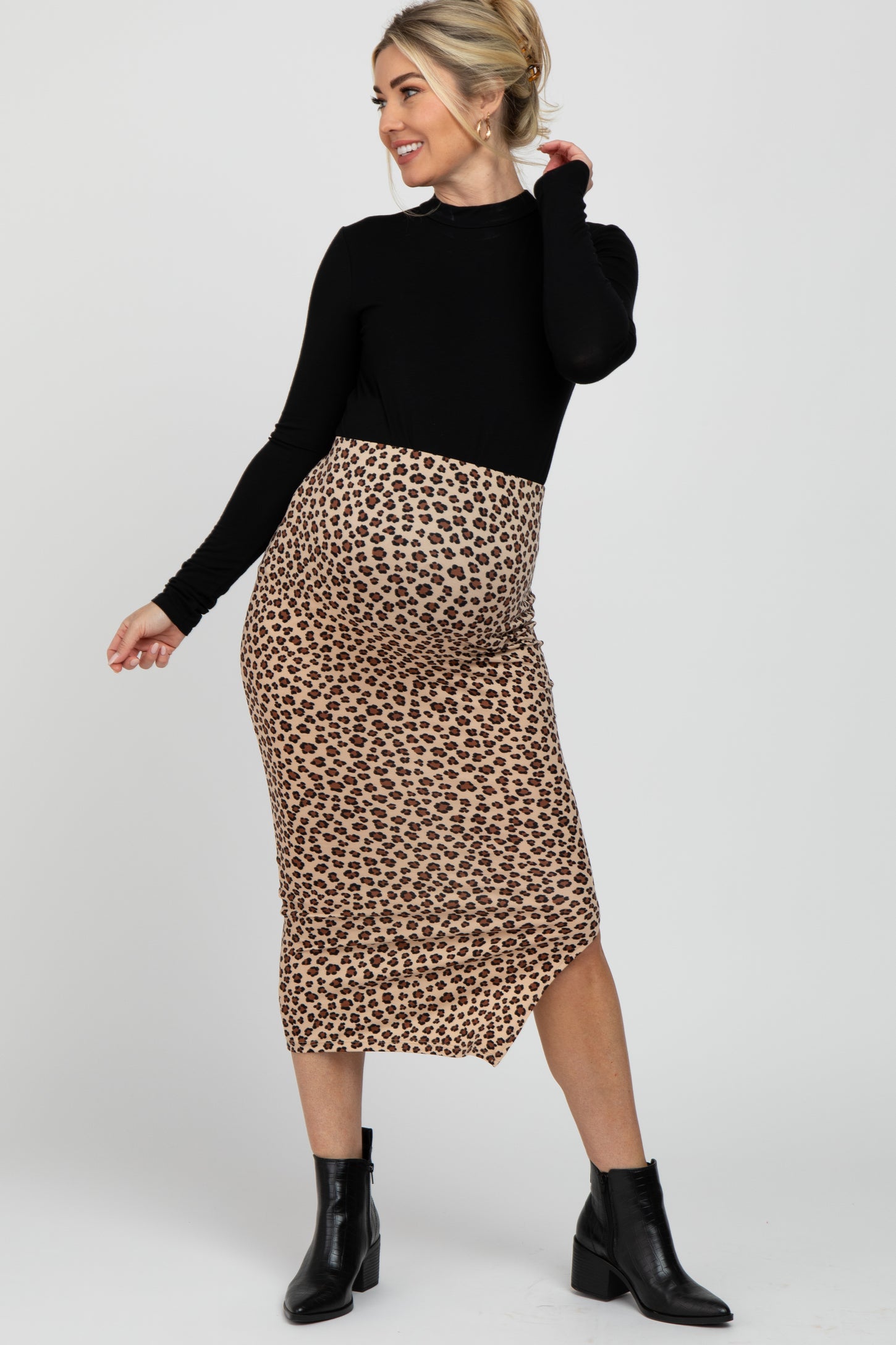 pregnant woman in black long sleeve top and leopard print maternity midi skirt with black ankle boots