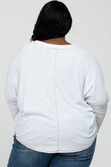 Back view of a person wearing a white long-sleeve waffle knit top with exposed seam detailing and blue jeans