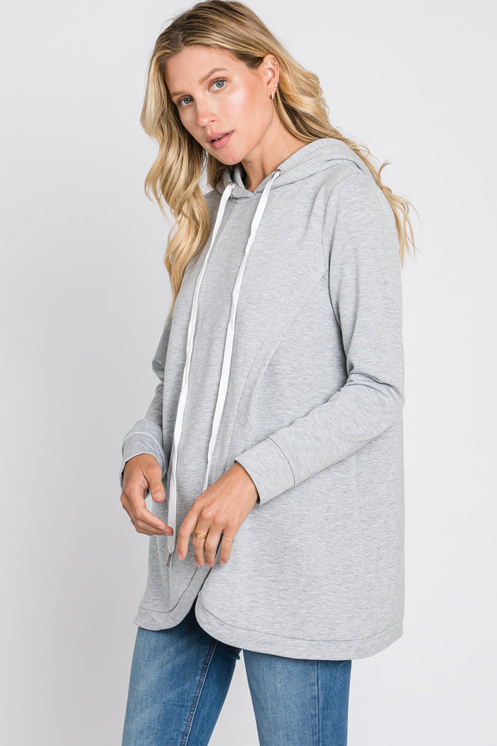 woman wearing a gray hooded pullover sweatshirt with a loose fit and white drawstrings