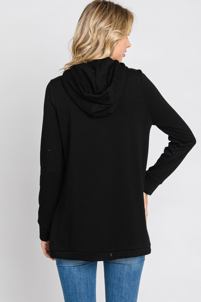 woman wearing a black hoodie with a long back and a drawstring hood, seen from the back, paired with blue jeans
