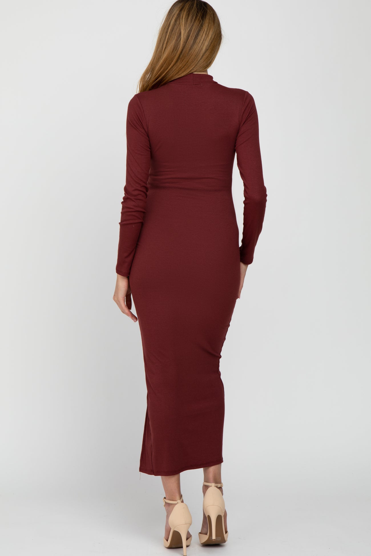 woman wearing a burgundy long sleeve fitted maternity dress with a side slit