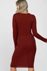 woman wearing a rust long sleeve ribbed maternity dress, showing a curve-hugging fit from the back