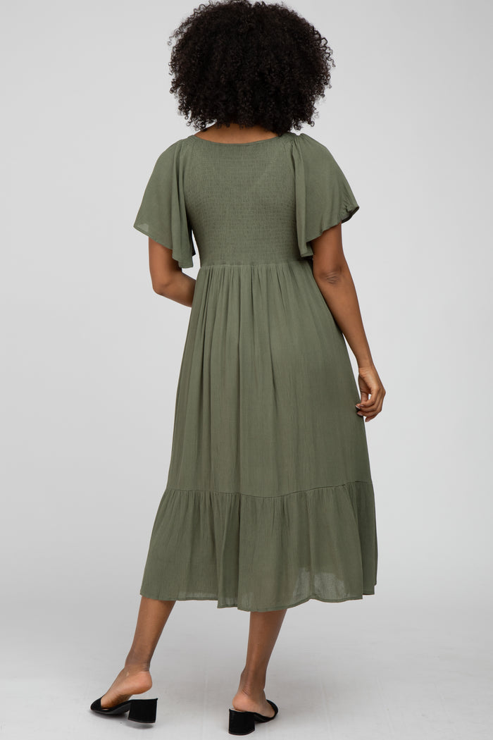 woman wearing a sage green midi dress with flutter sleeves and a tiered skirt, shown from the back