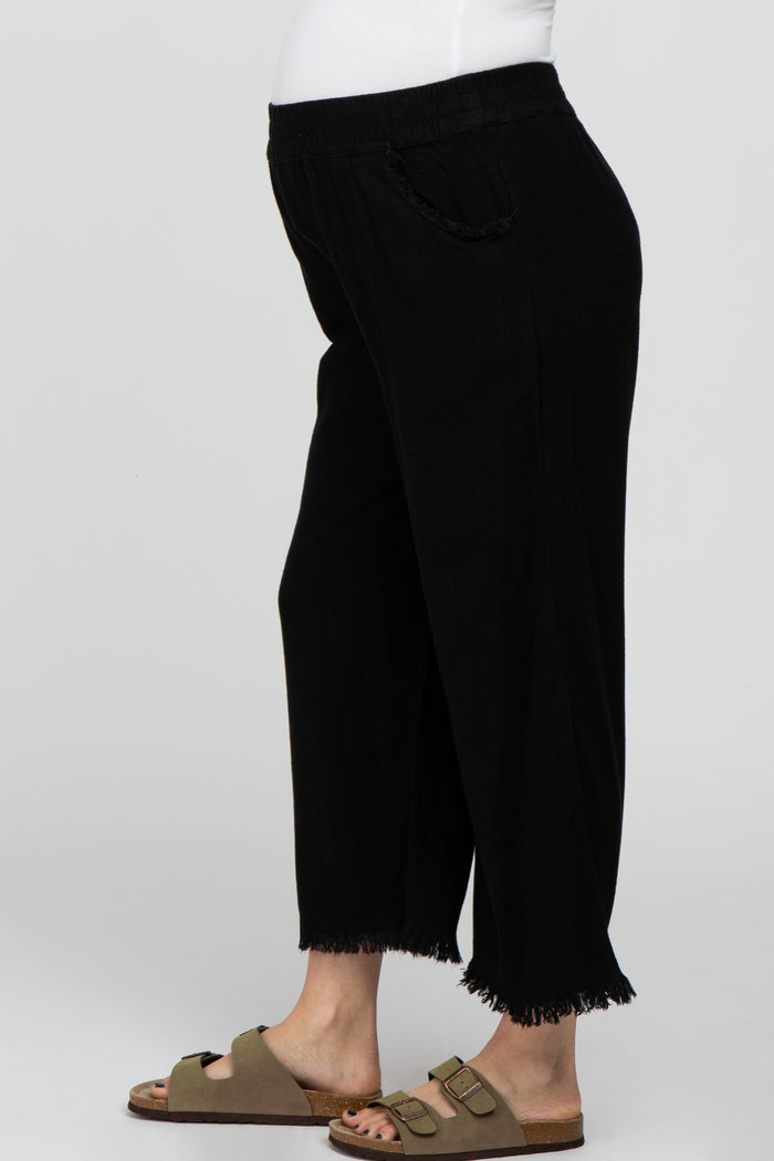 maternity wear black cropped pants with fringe details, model showing a baby bump and wearing sandals