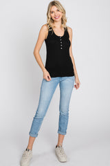 woman wearing a black ribbed henley tank top and light wash skinny jeans with white sneakers