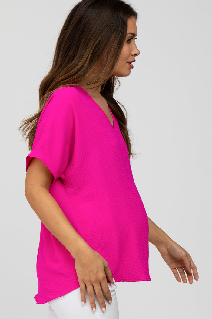 pregnant woman wearing a bright pink short sleeve maternity top and white pants