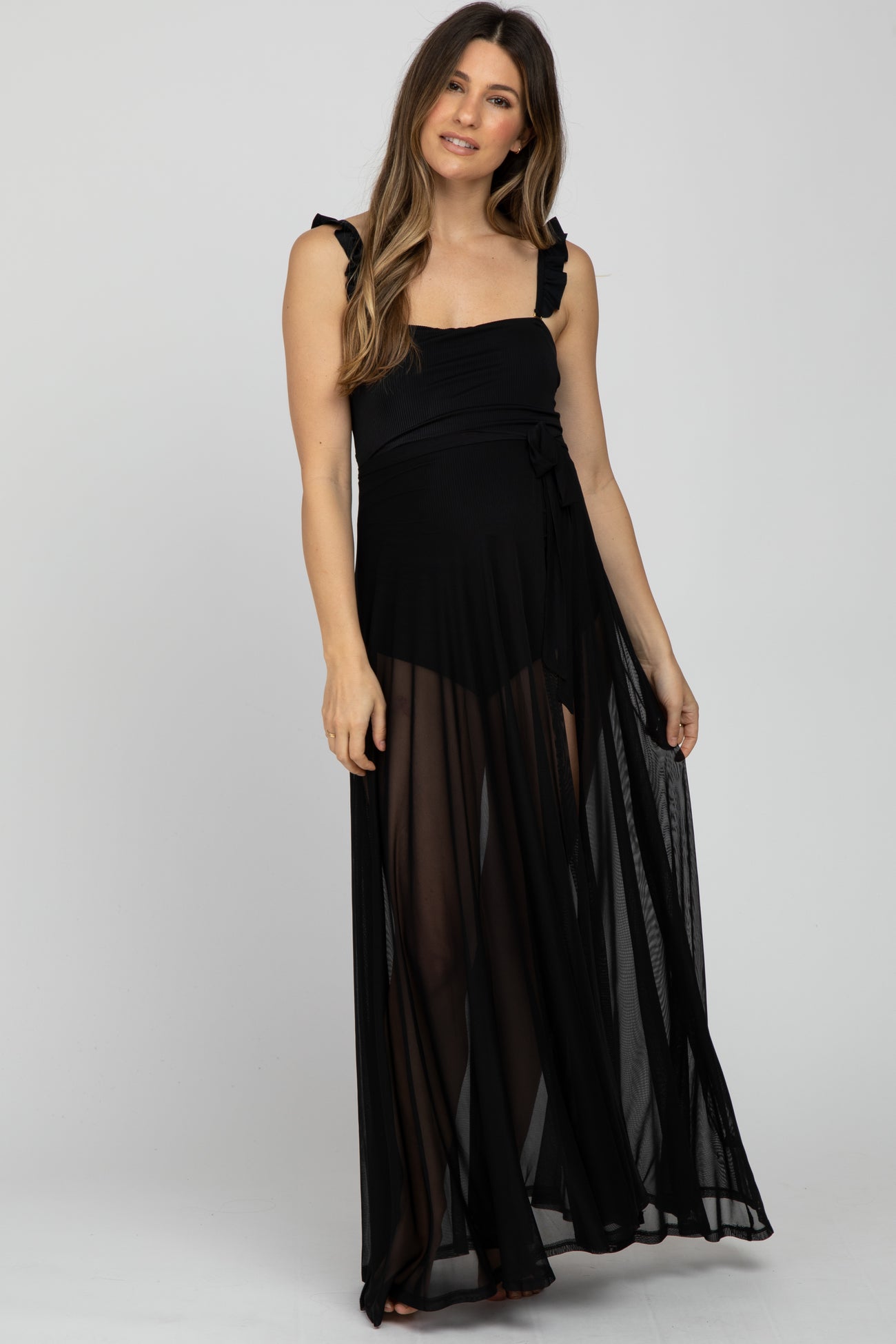 woman wearing a black maternity maxi dress with ruffle straps and a tie waist, showcasing a baby bump