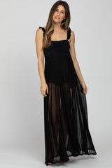 woman wearing a black maternity maxi dress with ruffle straps and a tie waist, showcasing a baby bump