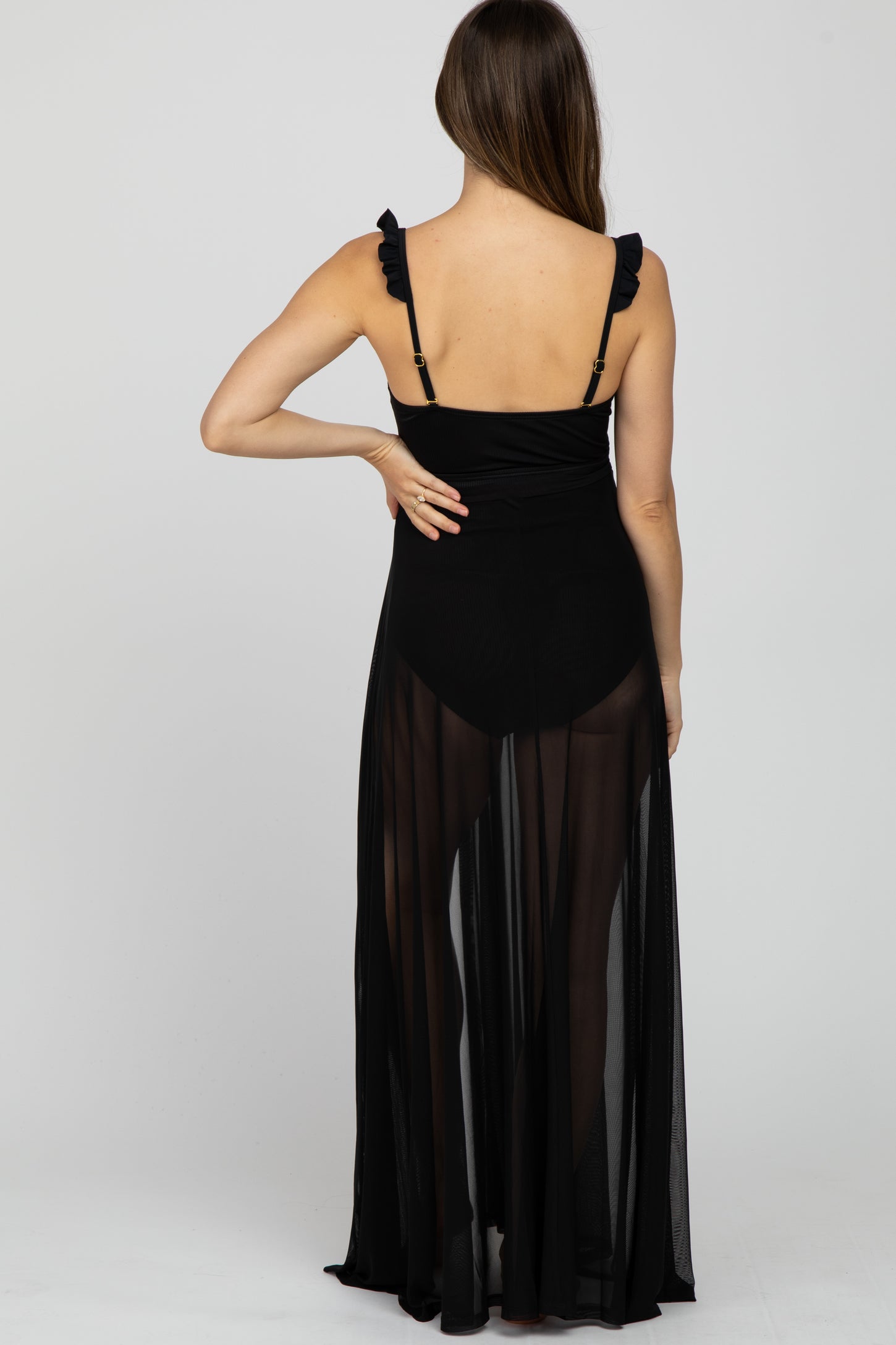 woman wearing a black maternity cover-up dress with ruffled straps, sheer fabric, and a flowy silhouette