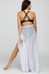 woman wearing a black maternity swimsuit top and a sheer white maternity cover-up skirt, showcasing her baby bump